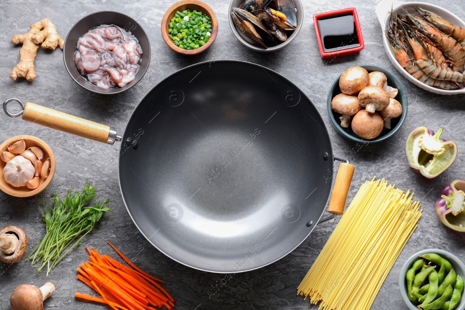 Photo of Different ingredients for wok on grey textured table, flat lay