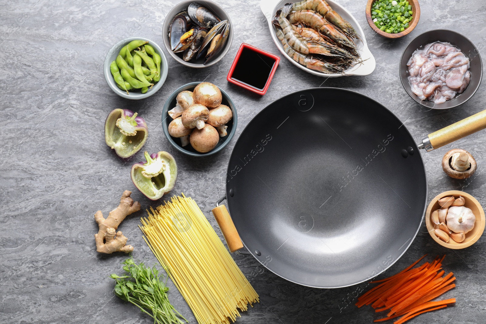 Photo of Different ingredients for wok on grey textured table, flat lay