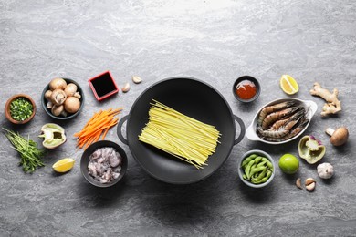 Different ingredients for wok on grey textured table, flat lay