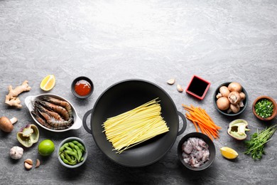 Different ingredients for wok on grey textured table, flat lay. Space for text