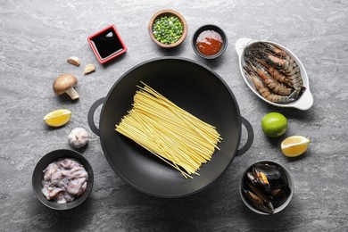 Photo of Different ingredients for wok on grey textured table, flat lay