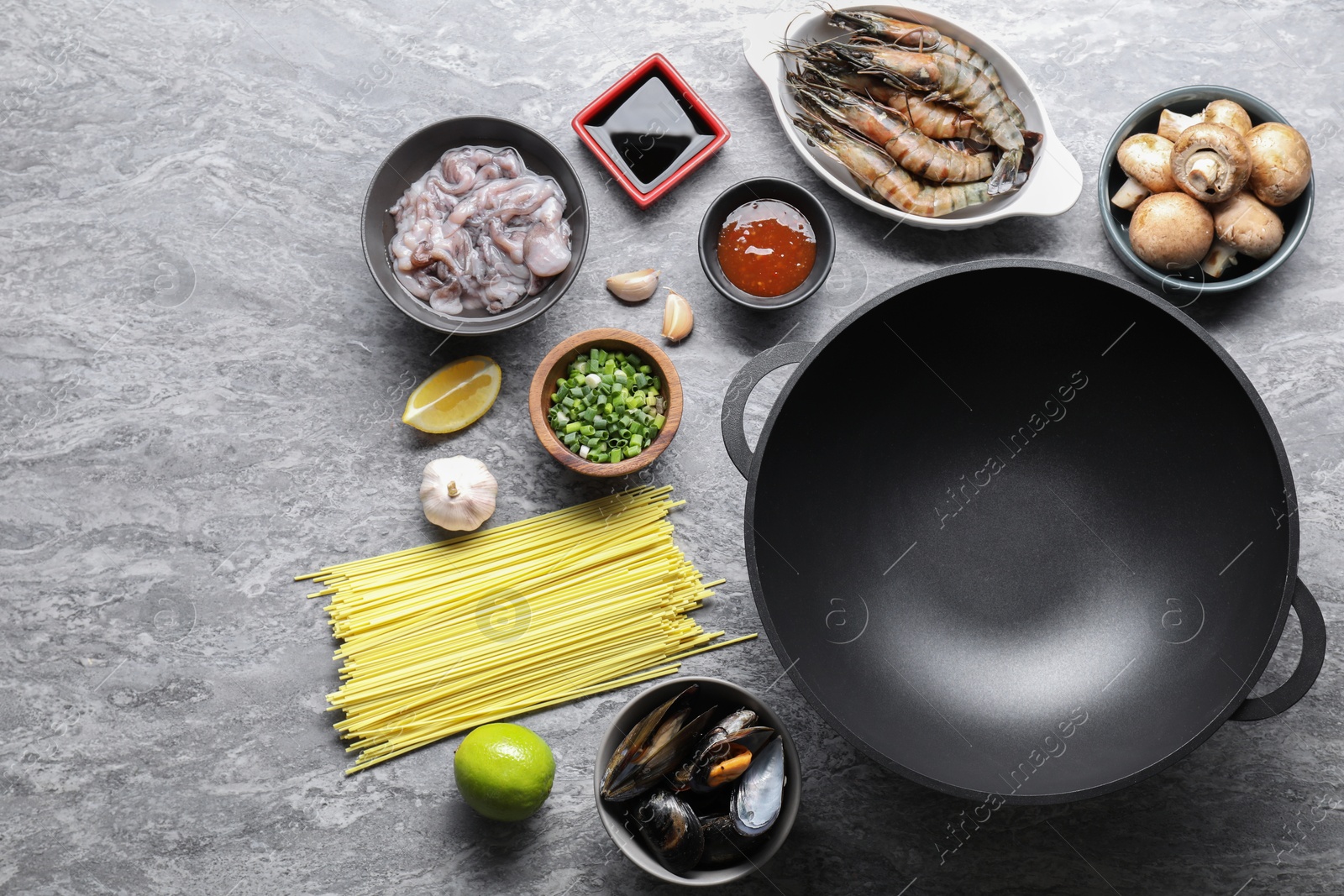 Photo of Different ingredients for wok on grey textured table, flat lay