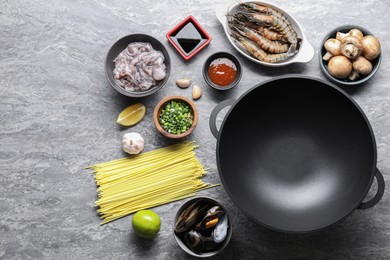 Different ingredients for wok on grey textured table, flat lay