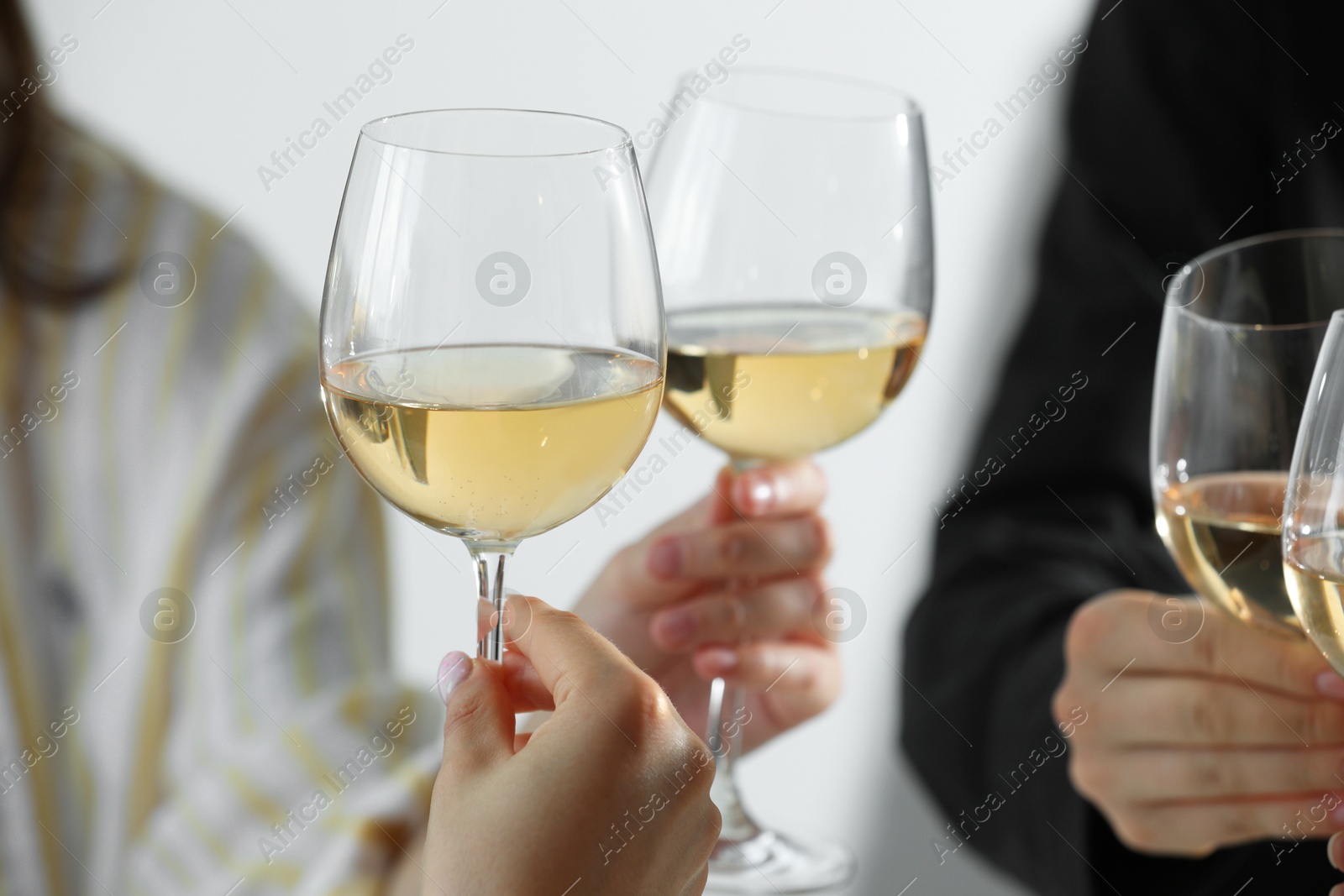 Photo of People clinking glasses of wine indoors, closeup