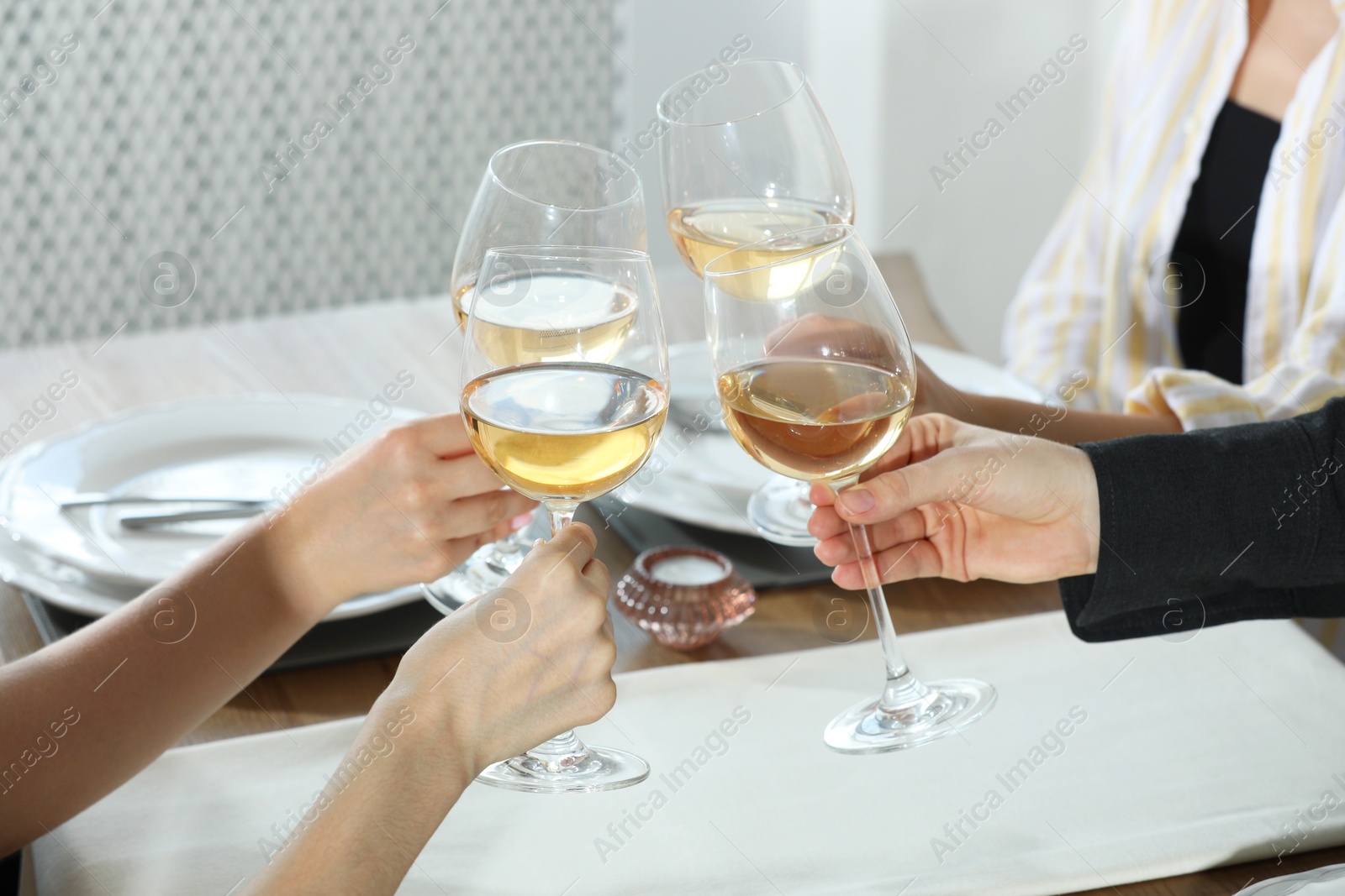 Photo of People clinking glasses of wine indoors, closeup