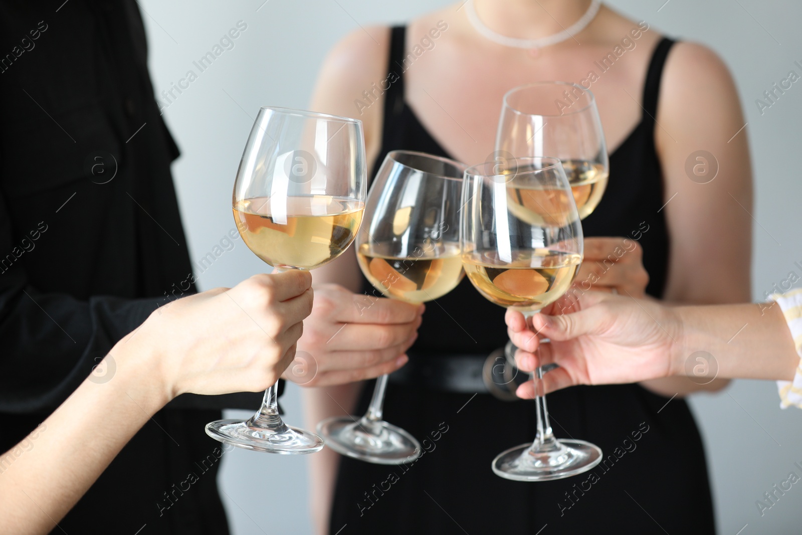 Photo of People clinking glasses of wine indoors, closeup