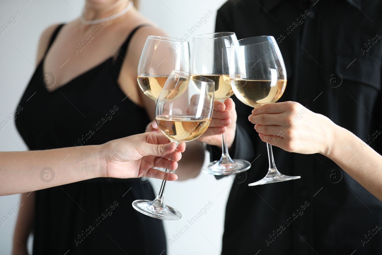 Photo of People clinking glasses of wine indoors, closeup