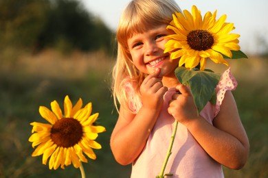 Photo of Little girl with sunflowers at meadow. Child enjoying beautiful nature