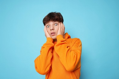 Photo of Scared teenage boy on light blue background