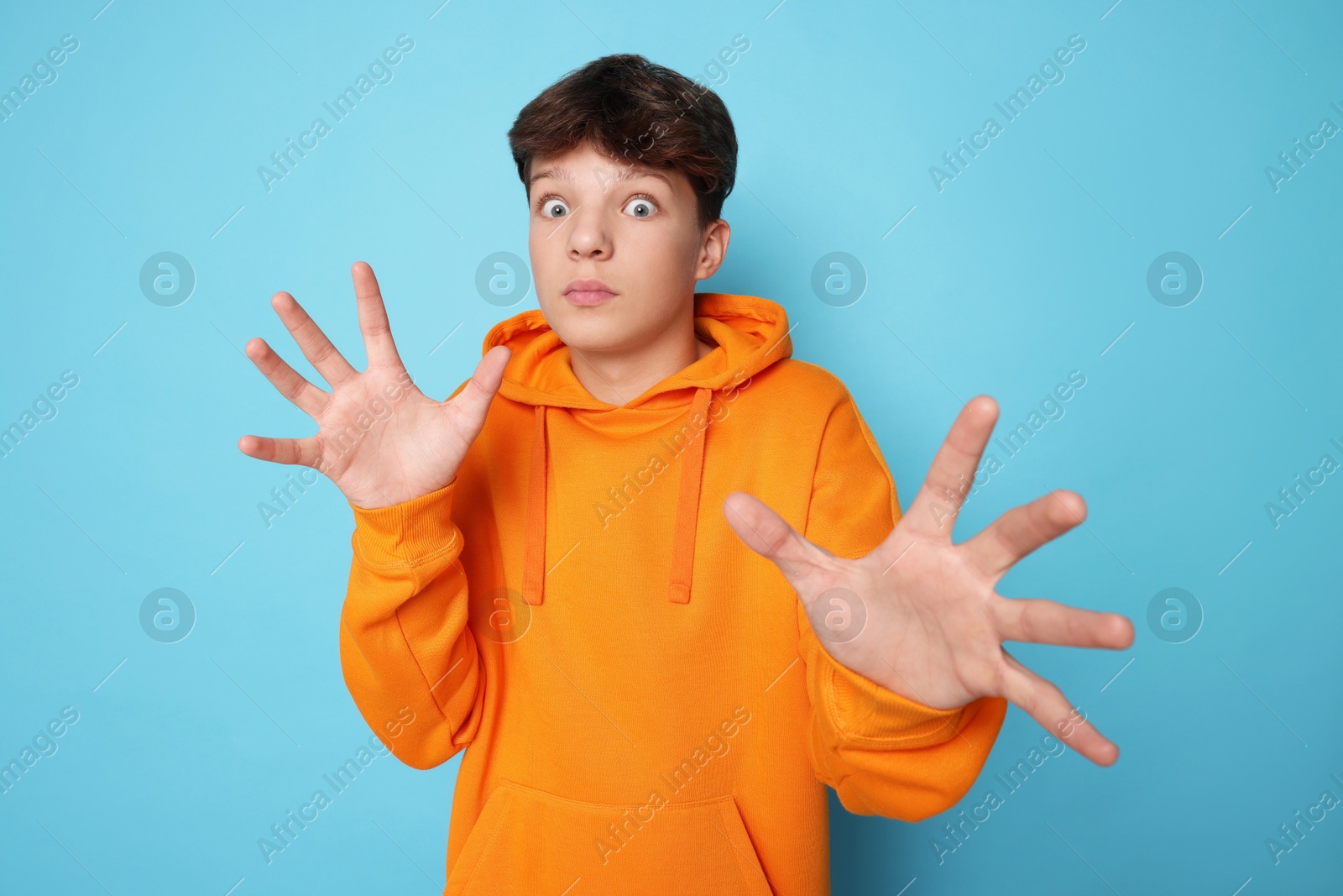 Photo of Scared teenage boy on light blue background