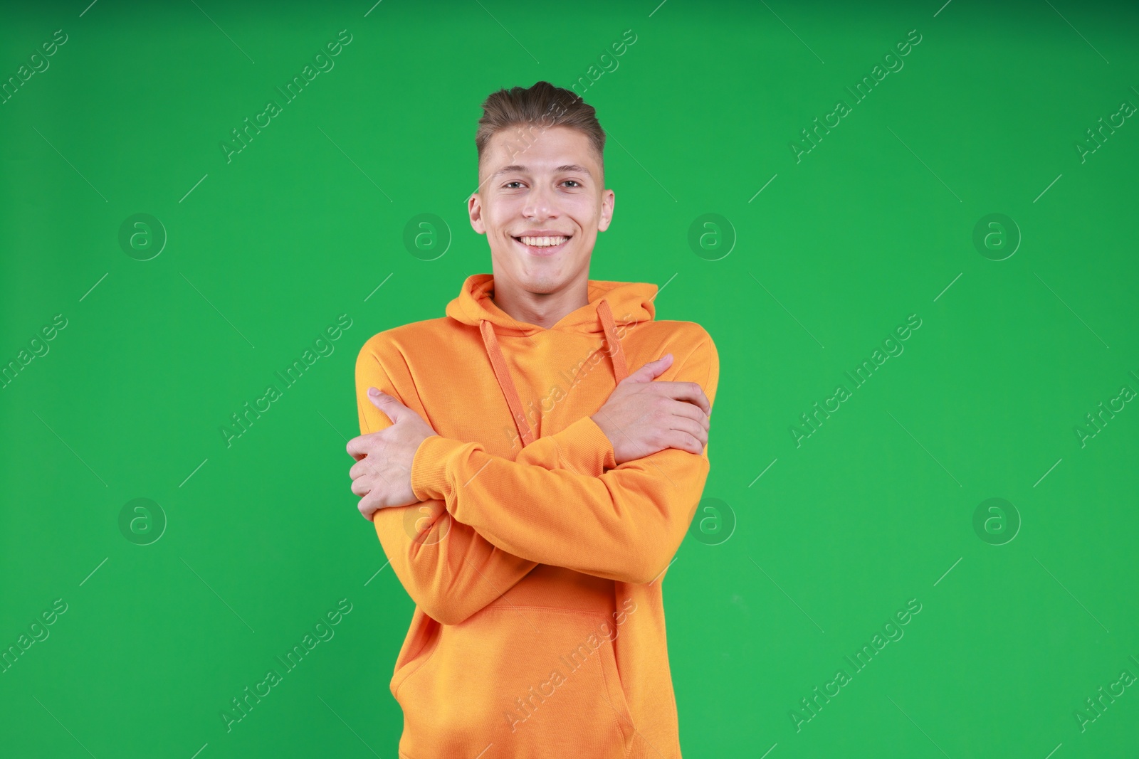 Photo of Young man hugging himself on green background