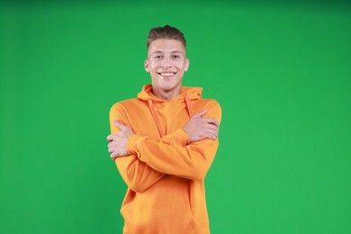 Young man hugging himself on green background