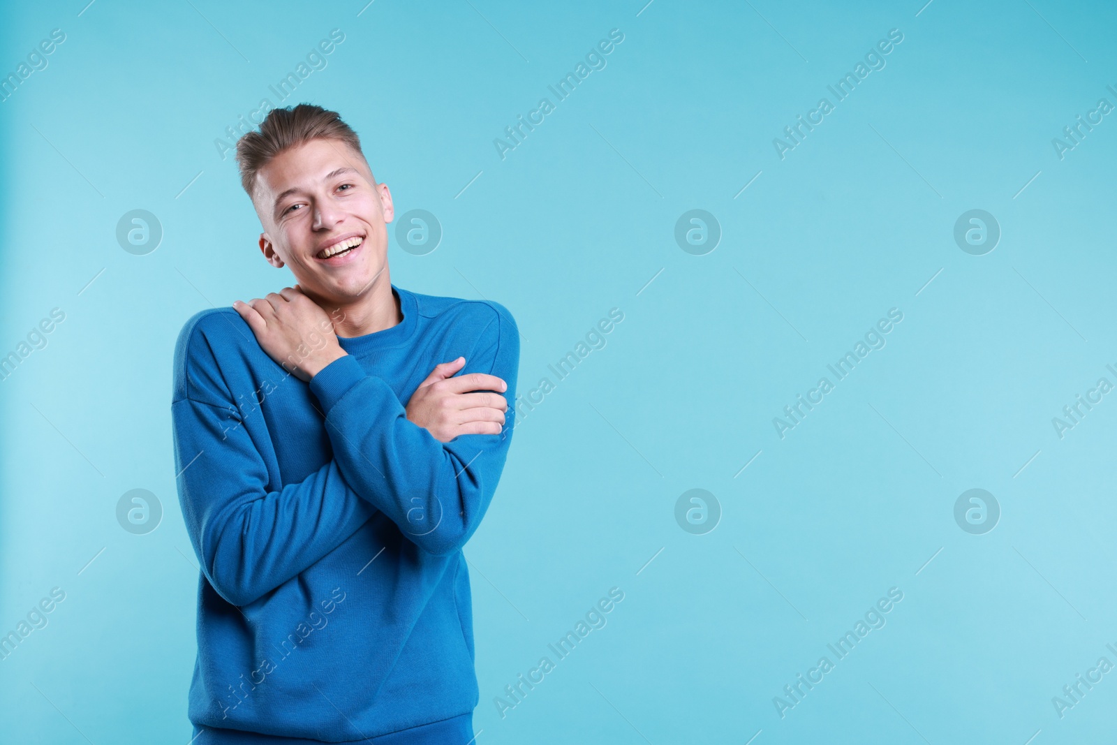 Photo of Young man hugging himself on light blue background, space for text