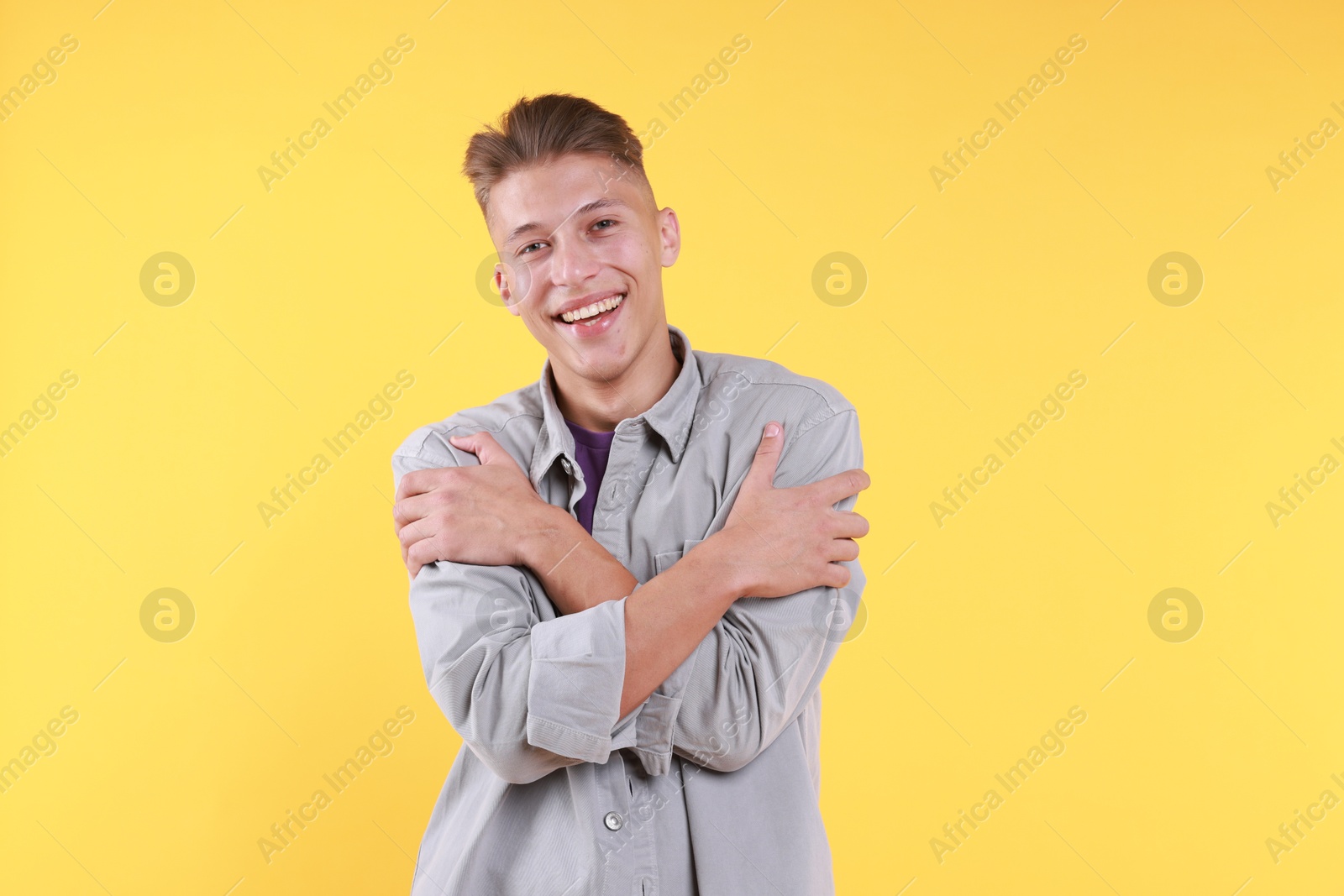 Photo of Young man hugging himself on yellow background