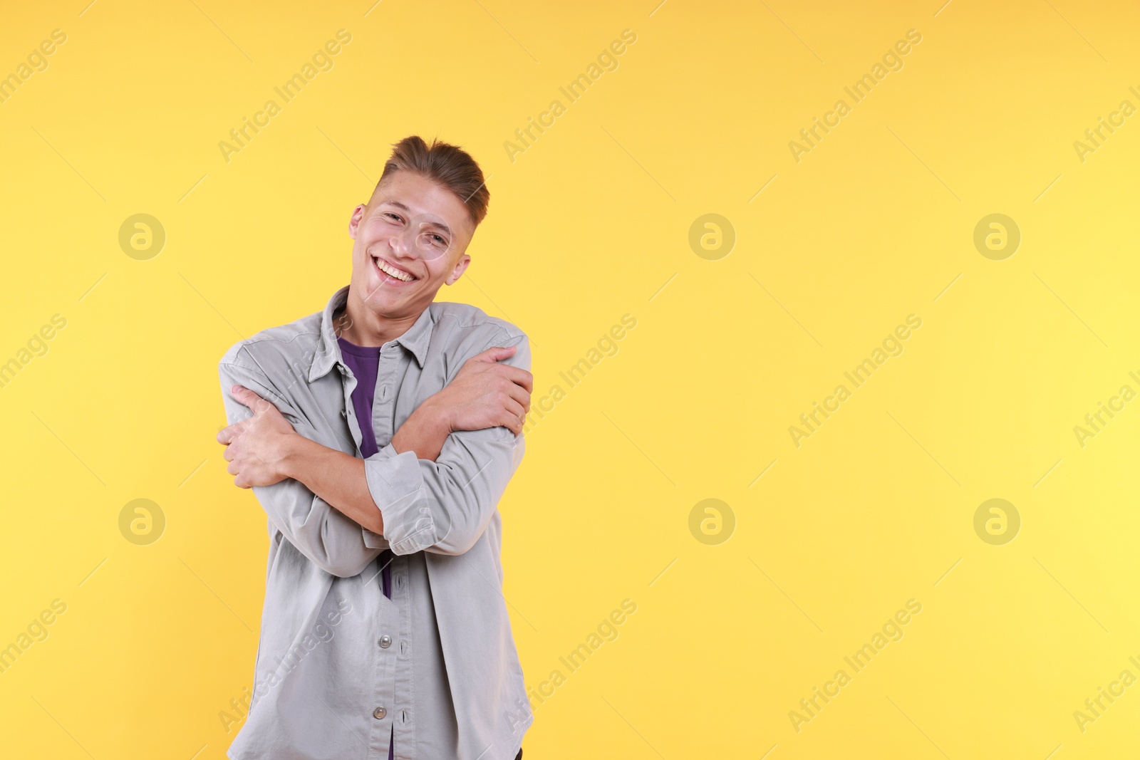 Photo of Young man hugging himself on yellow background, space for text