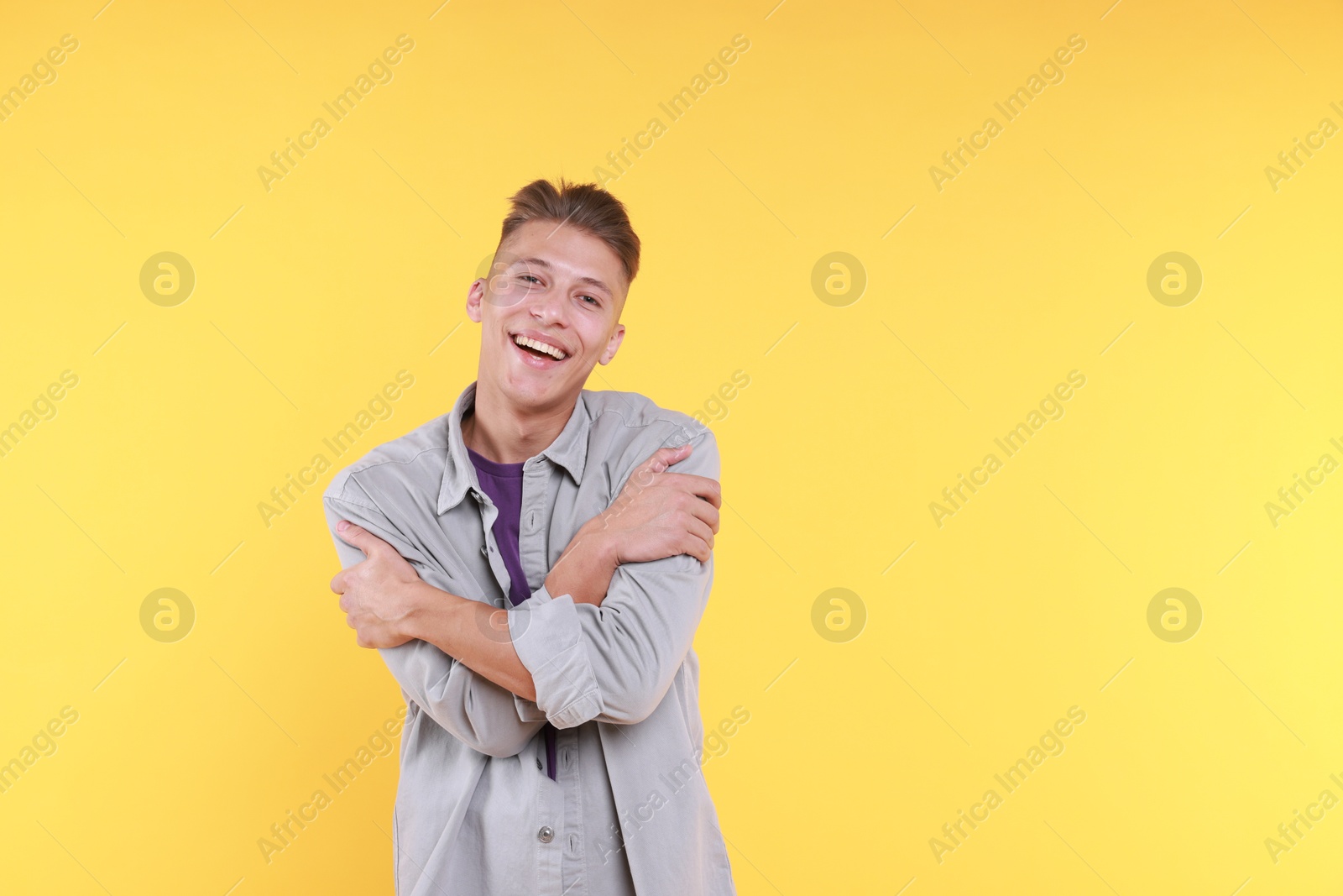 Photo of Young man hugging himself on yellow background, space for text