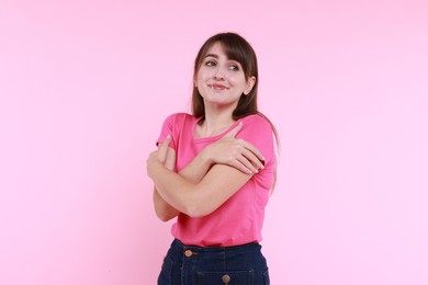 Photo of Young woman hugging himself on pink background