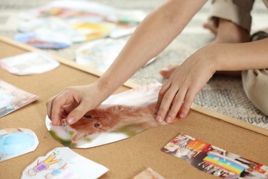 Photo of Little boy creating vision board with different pictures and other elements on floor indoors, closeup