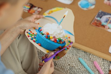 Photo of Creating vision board. Little boy cutting out picture indoors, closeup