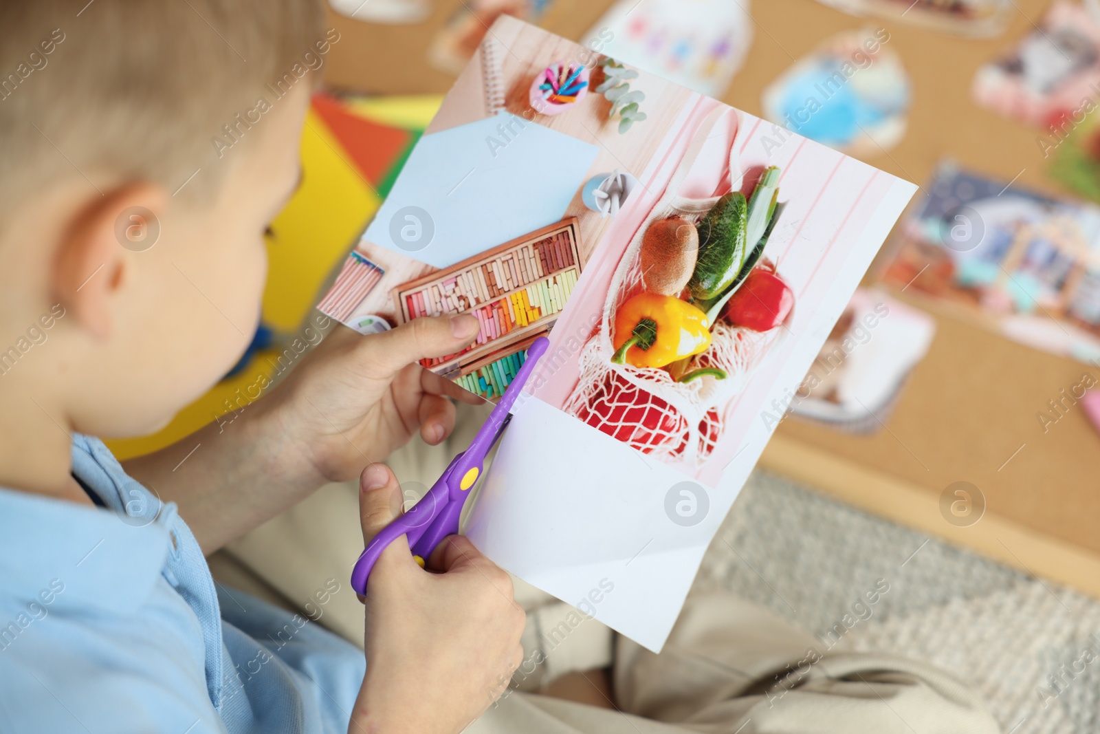 Photo of Creating vision board. Little boy cutting out picture on floor indoors