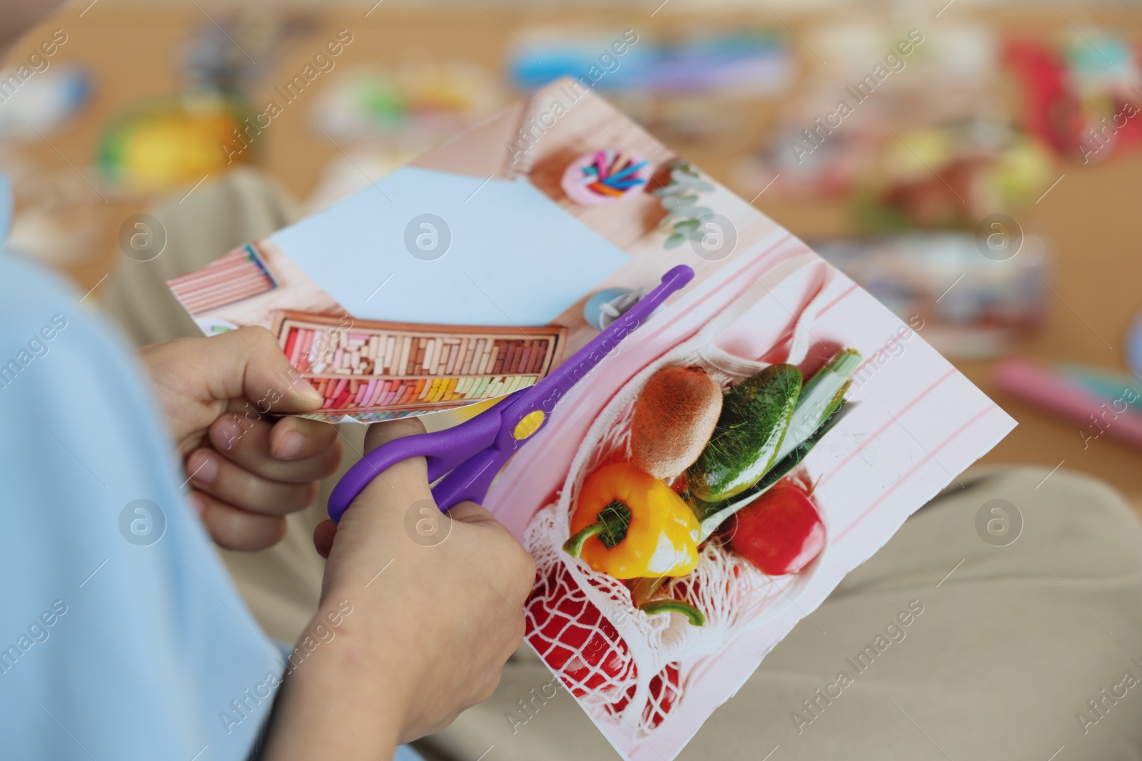 Photo of Creating vision board. Little boy cutting out picture indoors, closeup