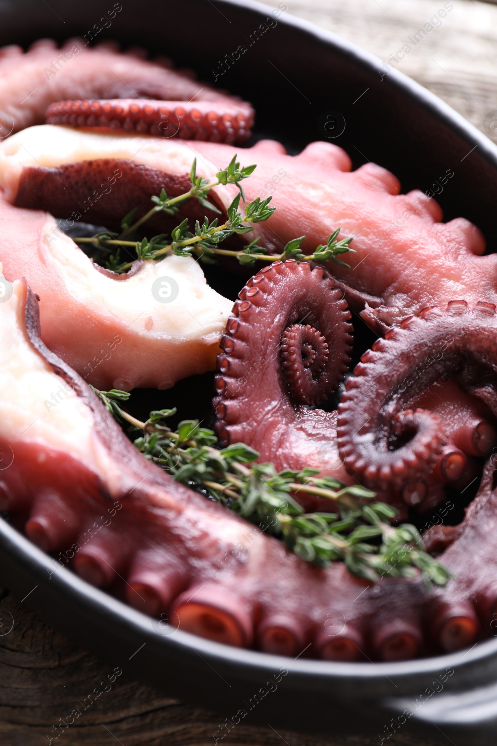 Photo of Fresh raw octopus and thyme in baking dish on table, closeup