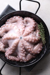 Fresh raw octopus and thyme in frying pan on grey table, top view