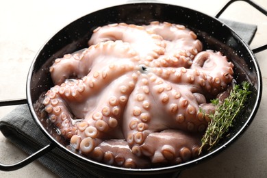 Photo of Fresh raw octopus and thyme in frying pan on grey table, closeup