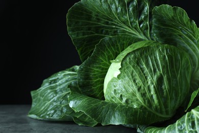 Photo of Whole ripe head of cabbage on table against dark background, closeup