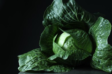 Photo of Whole ripe head of cabbage on table against dark background