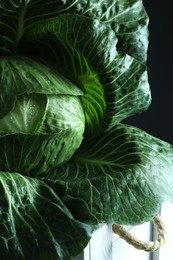 Photo of Whole ripe head of cabbage in crate on dark background, closeup