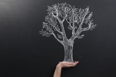 Photo of Woman pretending to hold tree drawn on chalkboard, closeup. Space for text