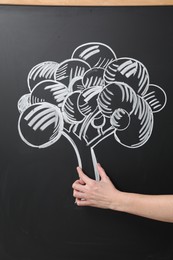 Woman pretending to hold tree drawn on chalkboard, closeup