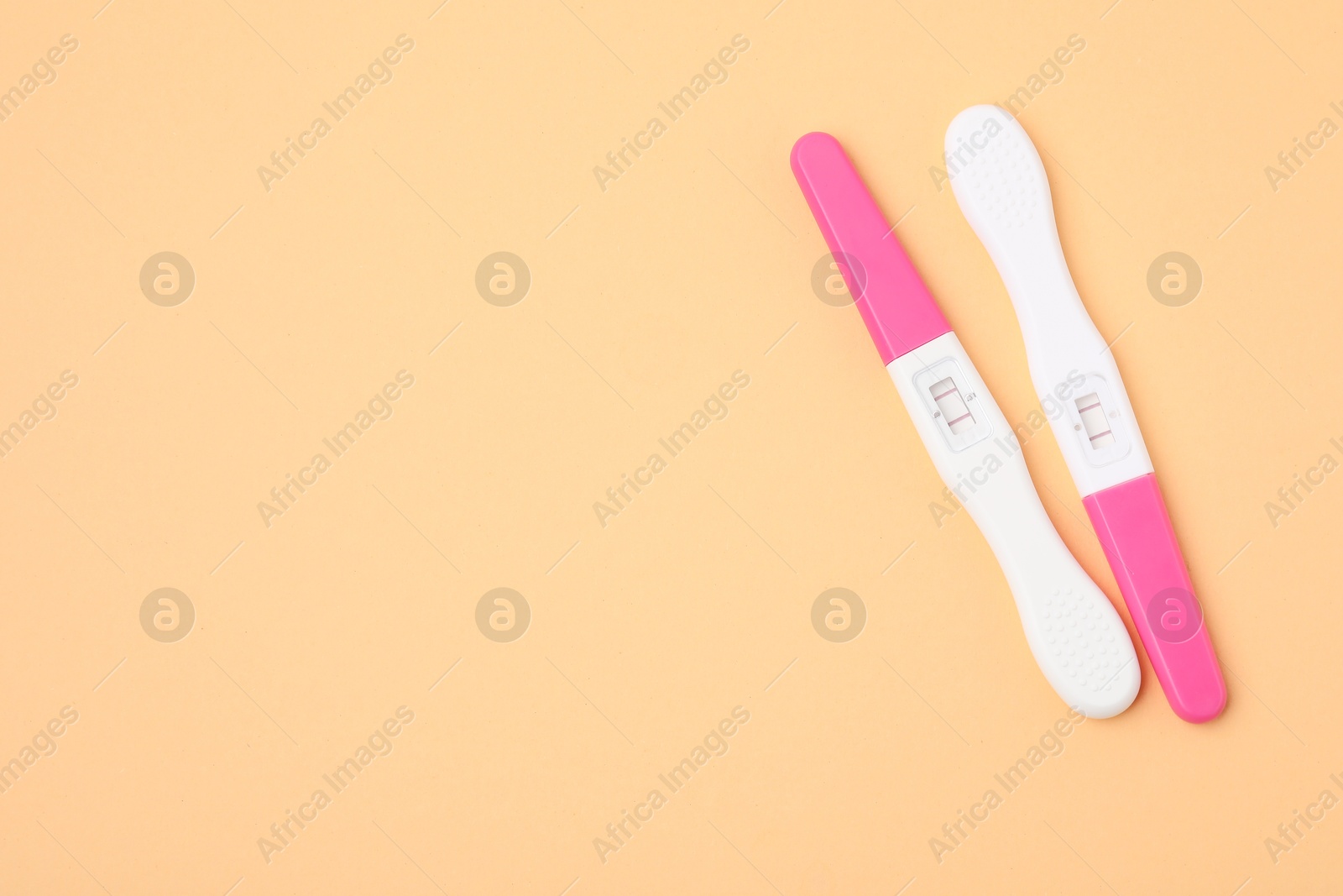 Photo of Pregnancy tests on pale orange background, top view. Space for text