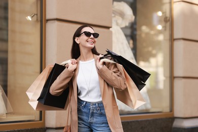 Photo of Happy woman with many shopping bags outdoors