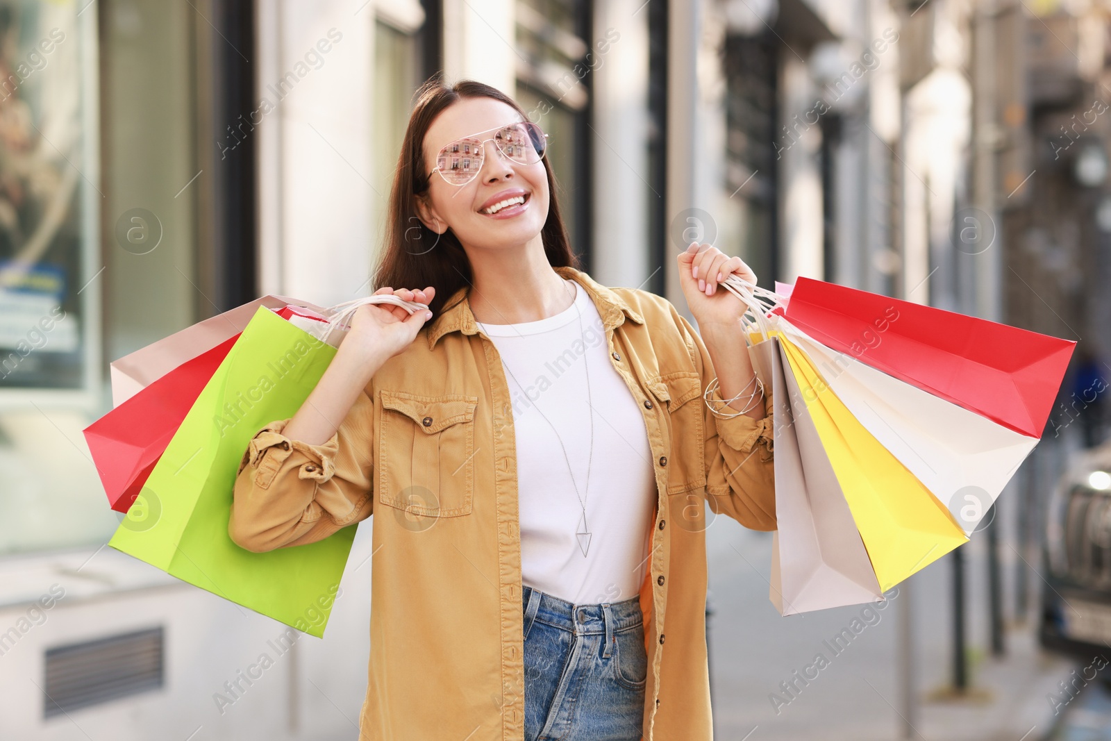 Photo of Happy woman with colorful shopping bags outdoors