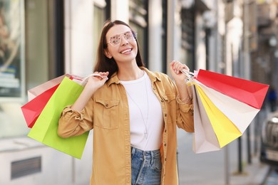 Happy woman with colorful shopping bags outdoors