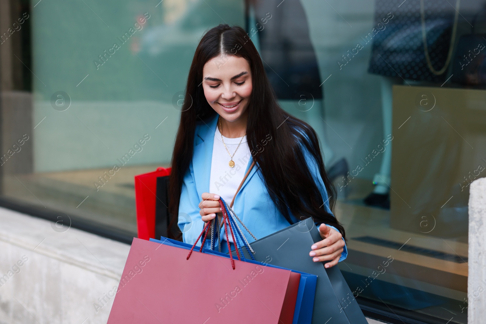 Photo of Happy woman with colorful shopping bags outdoors