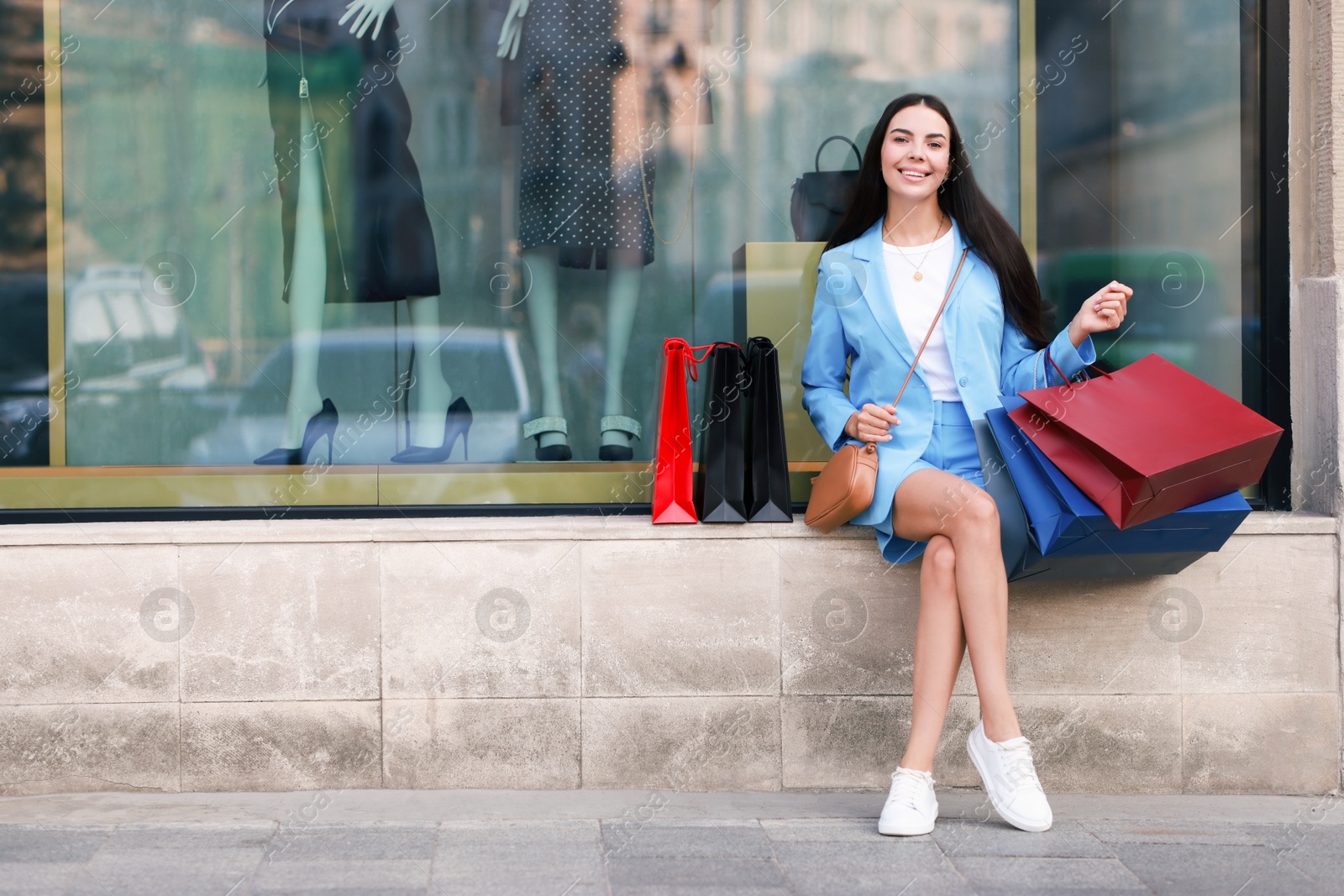 Photo of Happy woman with colorful shopping bags outdoors