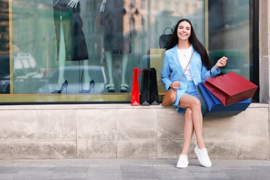 Happy woman with colorful shopping bags outdoors