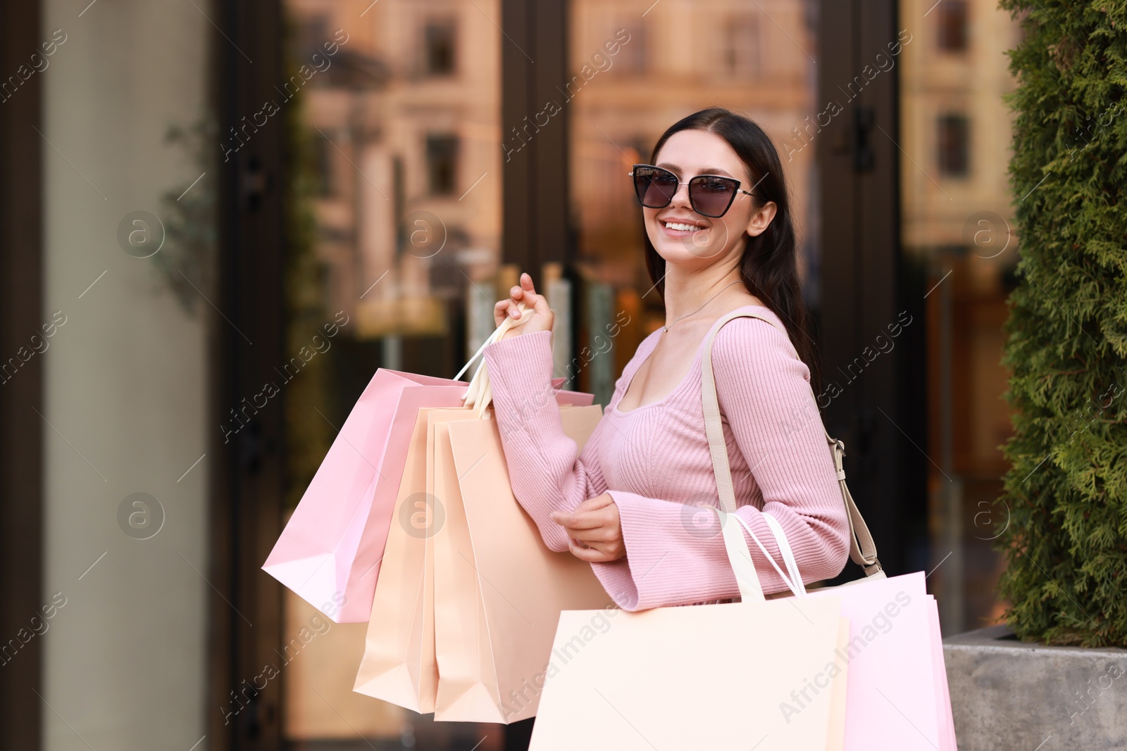 Photo of Happy woman with colorful shopping bags outdoors