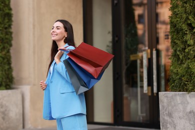 Photo of Happy woman with colorful shopping bags outdoors