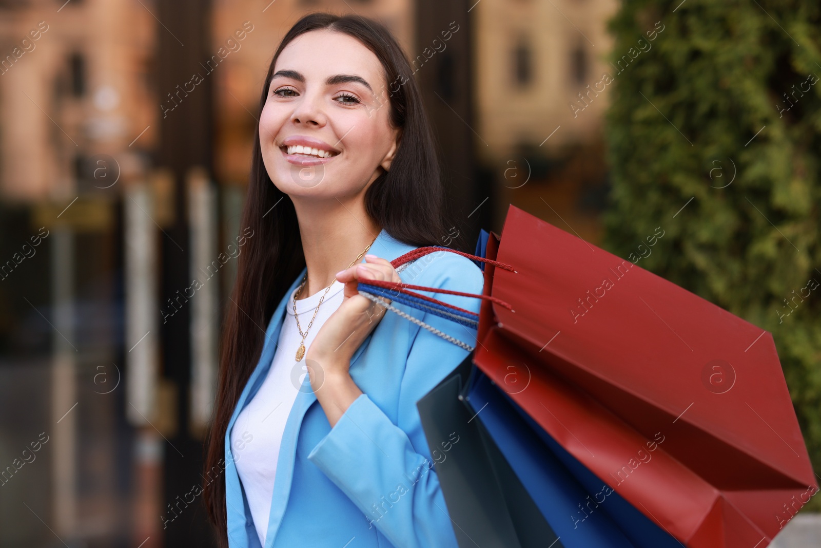 Photo of Happy woman with colorful shopping bags outdoors