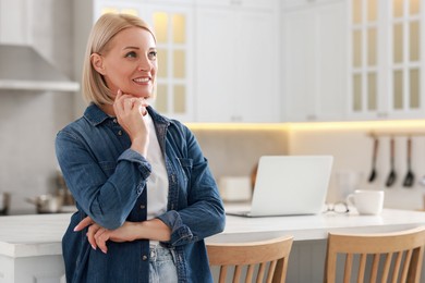 Happy middle aged woman in kitchen, space for text