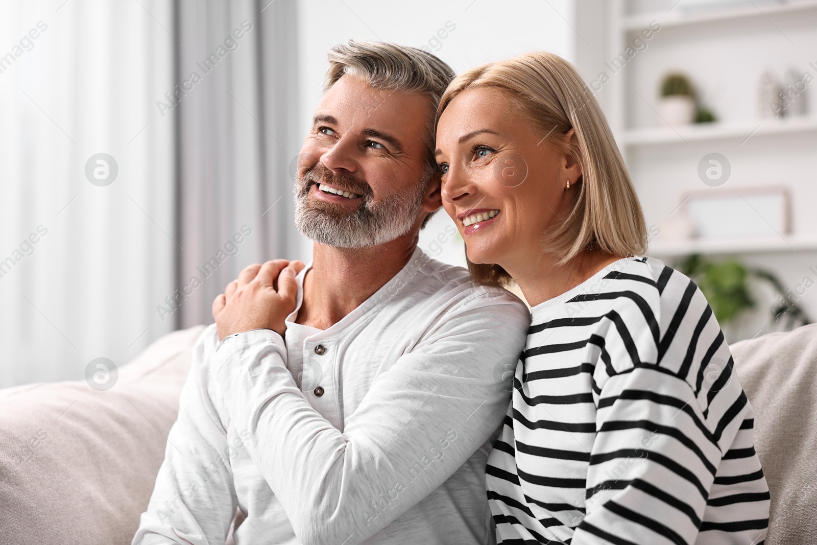 Photo of Happy middle aged couple on sofa at home