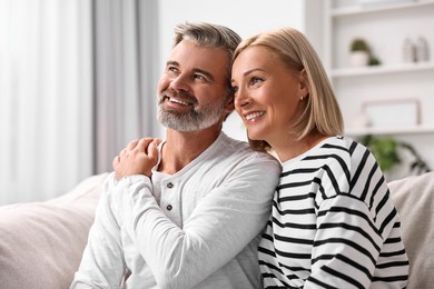 Photo of Happy middle aged couple on sofa at home