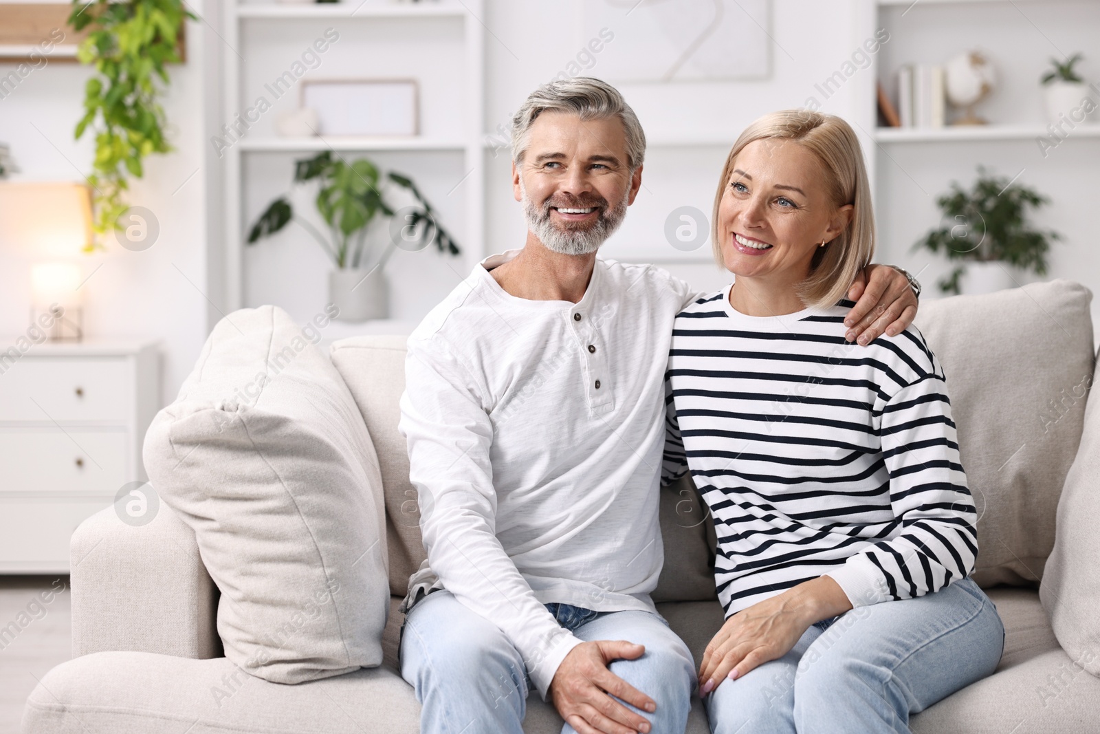 Photo of Happy middle aged couple on sofa at home