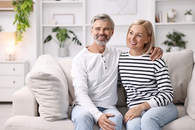 Happy middle aged couple on sofa at home