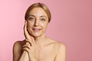 Portrait of smiling woman with healthy skin on pink background. Space for text