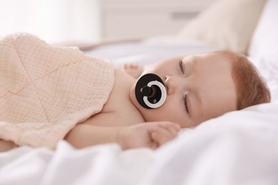 Cute little baby with pacifier sleeping on bed at home